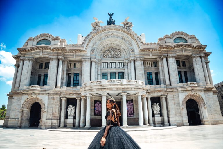 una mujer con un vestido negro parada frente a un edificio ornamentado.